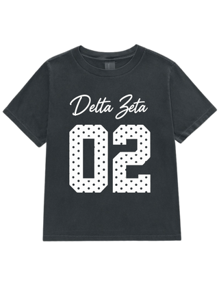 A dark gray short-sleeve t-shirt with 'Delta Zeta' in white script and the number '02' in a white polka-dot pattern, displayed on a solid white background.